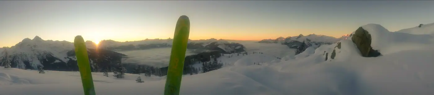 Zwei grüne Tourenski im Schnee, dahinter Sonnenaufgang über dem Nebelmeer